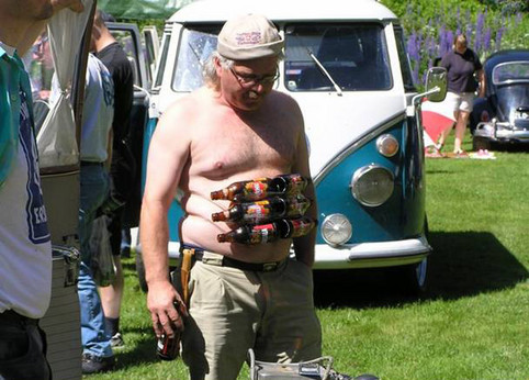 Ein alter Mann mit Bierflaschen als Sixpack vor seinem Bauch.